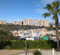 Pohled na obytné domy, stromy a kontejnery na ulici cl. Aquiles v Torrevieji.