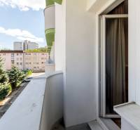 Balkon v garsonce na Ondavské ulici, Bratislava - Ružinov, s výhledem na zeleň a budovy.