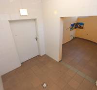 Kachličkovaná místnost s otvorem do vedlejší části, obchodní prostory s dlažbou.