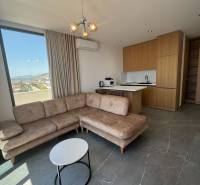 Obývací pokoj rekreačního apartmánu s rohovou sedačkou, výhledem a kuchyňským koutem.