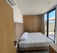 Ložnice v rekreačním apartmánu s pohodlnou postelí, vkusným zařízením a balkonem.