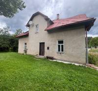 Rodinný dům v Makově na ulici Centrum, se zahradou a stromy v pozadí.