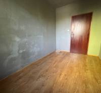 Pokoj s dřevěnou podlahou a šedými stěnami ve 3-pokojovém bytě.
