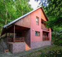 Chata v Ružinej obklopená zelení, s typickou architekturou a dřevěnými detaily.