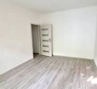 Prázdný pokoj s laminátovou podlahou v 2pokojovém bytě, neutrální stěny a stropní svítidlo.