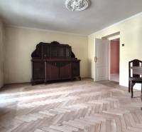 Pokoj ve 3-pokojovém bytě s dřevěným nábytkem a parketovou podlahou.