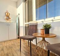 Balkon v 1-pokojovém bytě se dvěma židlemi, stolem a skříní na ukládání.