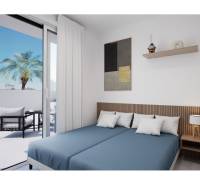 Ložnice rekreačního apartmánu s postelemi a přístupem na balkon s palmou.