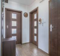 Chodba v 3-pokojovém bytě, obsahuje dveře, věšák a hodiny.