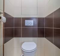 Toaleta s hnědo-bílými obklady v 3-pokojovém bytě.