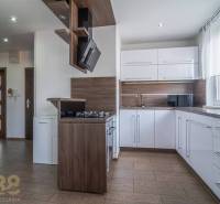 Kuchyně ve 3-pokojovém bytě s bílými skříňkami a dřevěnými doplňky.