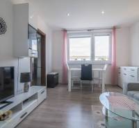 Světlý obývací pokoj se stolem, televizí a sedačkou v 3-pokojovém bytě.