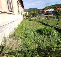 Zahrada rodinného domu v Nitrianskych Sučanoch s výhledem na ulici a kopce.