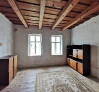 Pokoj v rodinném domě s dřevěným stropem, okna, skříňky, koberec na podlaze.