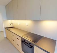 Kuchyně v 2pokojovém bytě s moderní pracovní deskou a vestavěnými spotřebiči.
