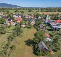 Letecký pohled na obecní pozemky na bydlení v Sečovcích obklopené zelení a domy.