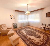 Obývací pokoj v rodinném domě, křesla, koberec s ornamenty a závěsné svítidlo.