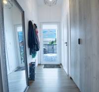 Chodba v rodinném domě s velkým zrcadlem, věšáky a skříní.