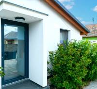 V Černé Vodě se nachází rodinný dům s bílou fasádou obklopený zelenými keři.