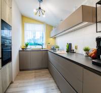 Kuchyně v rodinném domě s moderními skříňkami, spotřebiči a světlým oknem.