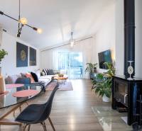 Obývací pokoj rodinného domu s krbem, pohodlnou pohovkou a skleněným stolem.