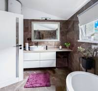 Koupelna v rodinném domě s vanou, umyvadlem a oknem, dekorativní rostliny.