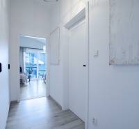 Úzká světlá chodba v rodinném domě s výhledem na pokoj a terasu.