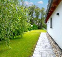 Rodinný dům v Černé Vodě s udržovanou zahradou a chodníkem podél budovy.