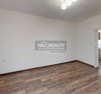 Prázdný pokoj s dřevěnou podlahou v 3-pokojovém bytě, bílé stěny, posuvné dveře.