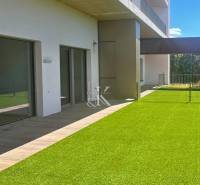 Terasa s umělým trávníkem a posuvnými dveřmi Rekreačního apartmánu v Banke.