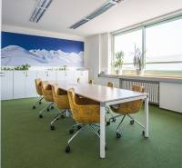 Kanceláře se zeleným kobercem, žlutými židlemi a velkou fototapetou hor.