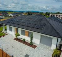 Rodinný dům v Piešťanech s fotovoltaickými panely na střeše obklopuje zelená zahrada.