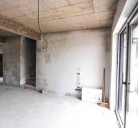 Interiér nedokončeného rodinného domu, betonové stěny a schody vedou do patra.
