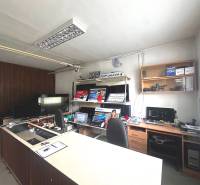 Kancelářské obchodní prostory s pultem, počítači a policemi s elektronikou.