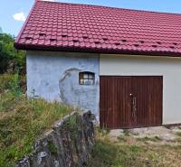 Rodinný dům na Dlouhé ulici ve Vranově nad Topľou s červenou střechou a dřevěnou garáží.