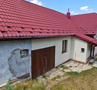 Rodinný dům na Dlouhé ulici ve Vranově nad Topľou s červenou střechou a garážovými vraty.