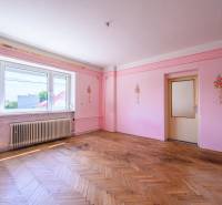 Růžové stěny s květinovou výzdobou, dřevěná podlaha, velké okno v rodinném domě.