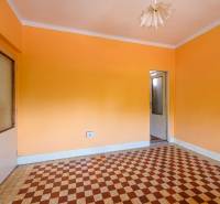 Pokoj v rodinném domě s oranžovými stěnami a dlaždičkovým vzorem na podlaze.