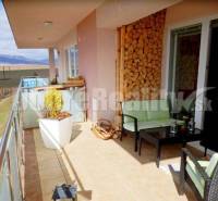 Balkon 2pokojového bytu s výhledem na přírodu, pohodlným sezením a dekorativním dřevem.