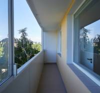 Zasklený balkon v 2-pokojovém bytě s výhledem na zeleň.