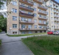 Bytový dům ve Vysokých Tatrách s balkóny a parkovištěm před budovou.