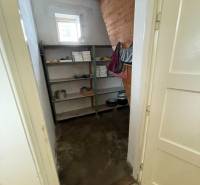 Spíž v rodinném domě s regály, otevřeným oknem a dřevěným obkladem stěny.