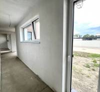 Chodba s okny a vstupem v rodinném domě. Na podlaze je beton.