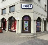 Komárno, ulice Petőfiho, obchodní prostory s reklamními tabulemi a několika vchody.