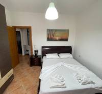Ložnice v rekreačním apartmánu s dvojlůžkem, skříněmi a dekoračním obrazem na stěně.
