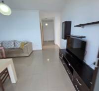 Obývací pokoj s pohovkou, televizí a jídelním stolem v rekreačním apartmánu.