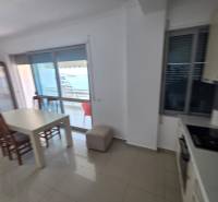Jídelní kout s výhledem na moře v rekreačním apartmánu, světlé interiérové zařízení.