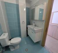 Koupelna se světle modrými dlaždicemi v Rekreačním apartmánu, umyvadlo a zrcadlová skříňka.