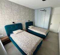 Dvoulůžkový pokoj s modrými postelemi a vzorovanou stěnou v Rekreačním apartmánu.