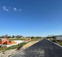 Stavební pozemek rodinného domu v Horním Baru s cihlami a novou asfaltovou cestou.